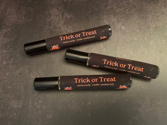 Three black lip gloss tubes with 'Trick or Treat' text on a dark surface